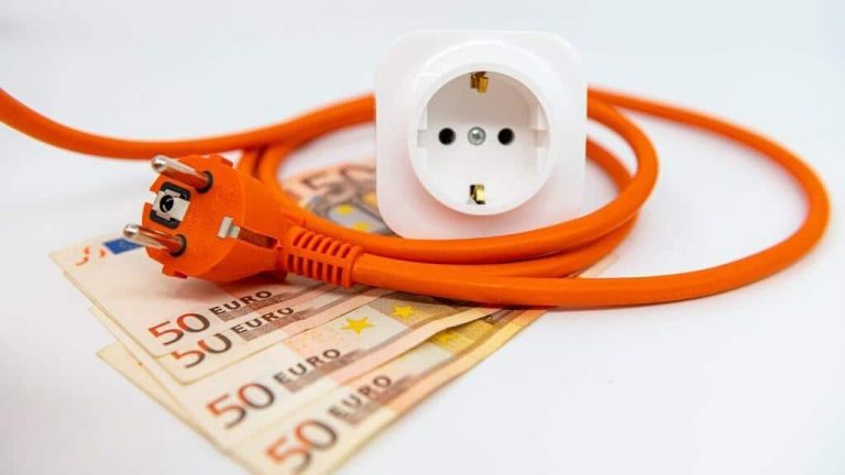 Een oranje stekken met snoer is om een stekkerblok gerold met daar onder vier briefjes van 50 euro biljetten