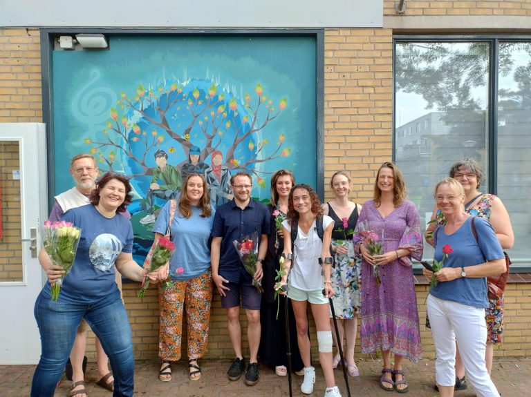 Mensen voor de gekleurde muurschildering bij Enik Recovery College Nieuwegein