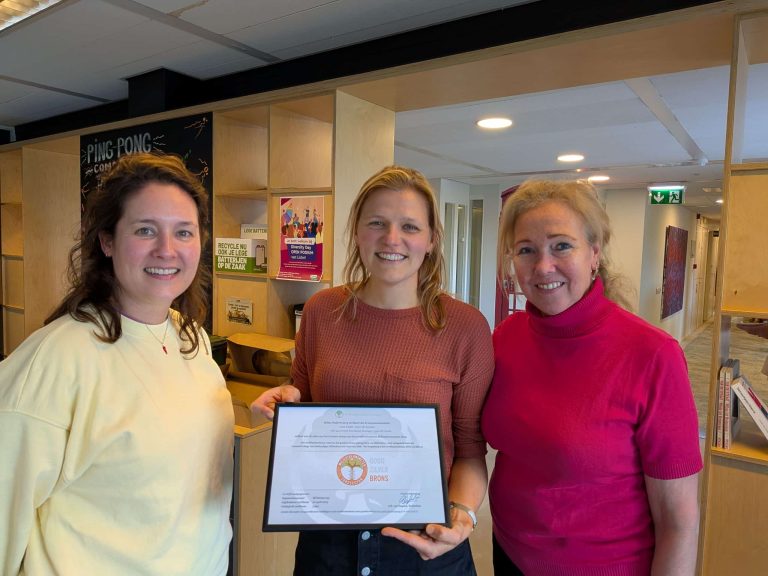 drie medewerkers kijken in de camera waarvan even met certificaat in handen