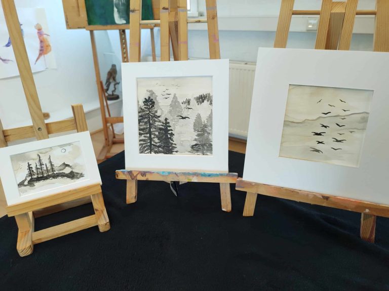 Drie schilderijen op een schildersezel staan tentoongesteld