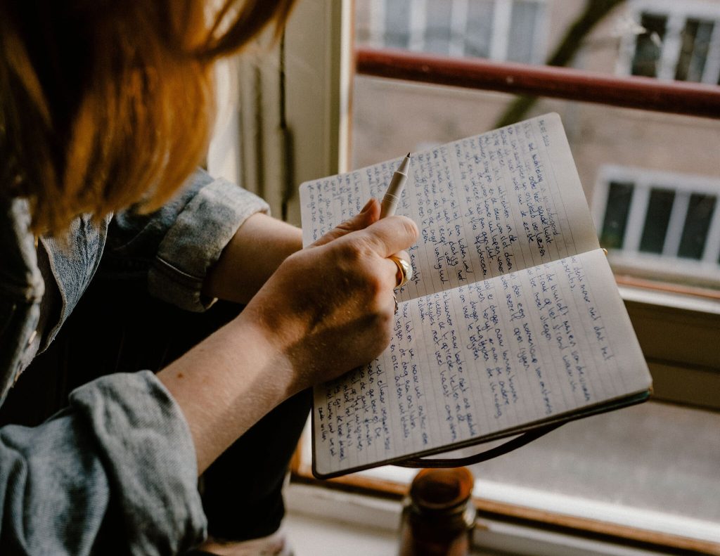 hand met pen bij notitieboek