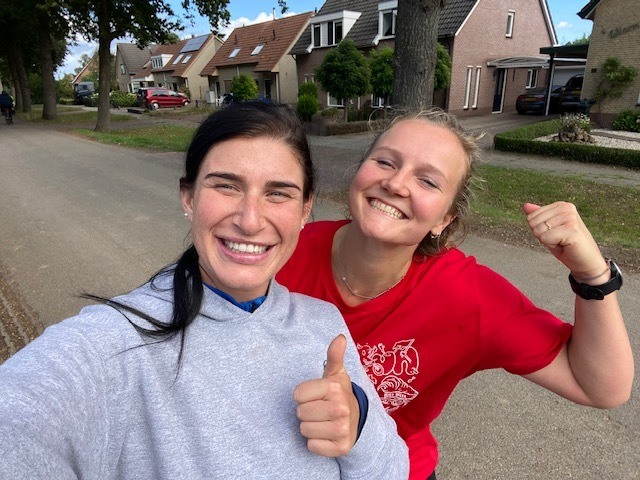 Twee vrouwen kijken de camera in en hebben allebei hun linkerduim op.