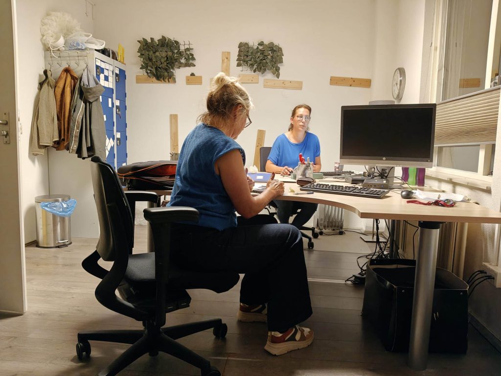 twee vrouwen zitten aan even bureau in aan kantoor