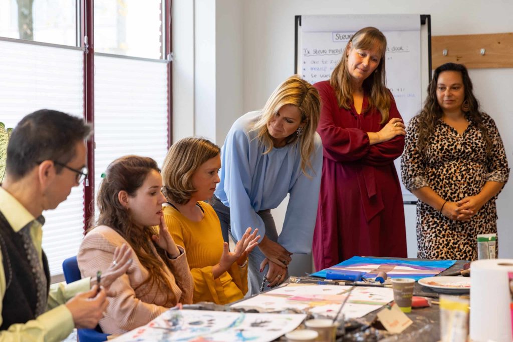 Maxima staat gehurkt in gesprek met deelnemers bij Enik