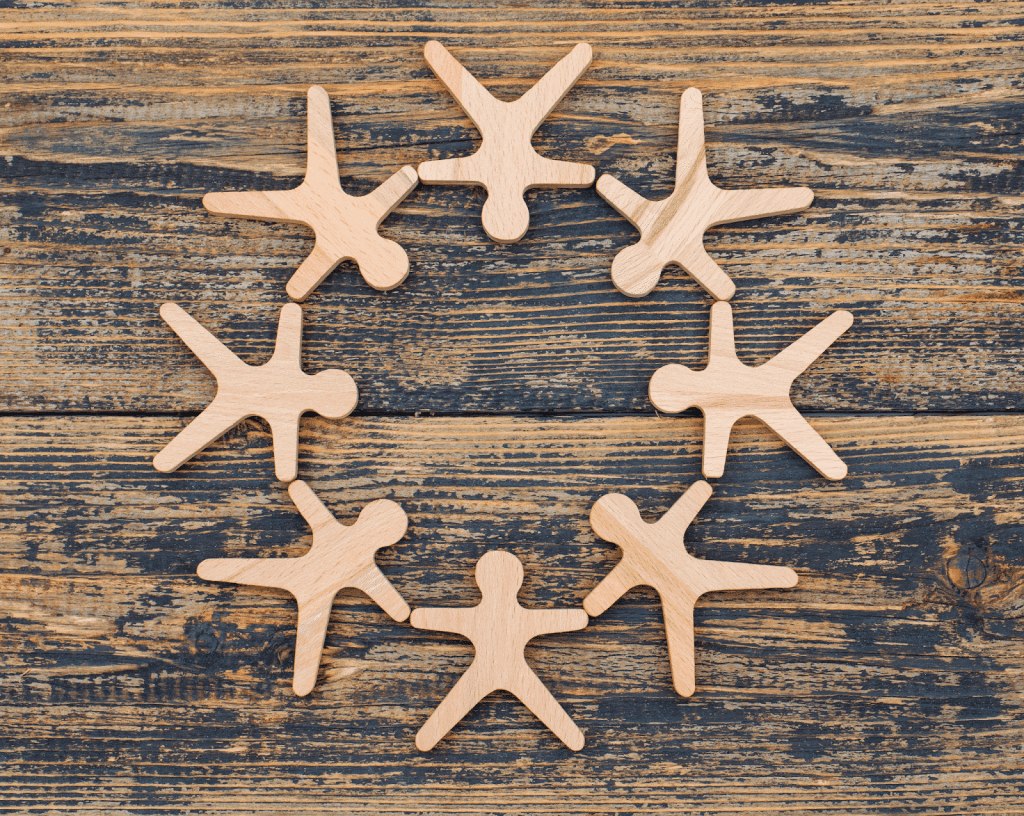 Uit papier geknipte poppetjes die handen vasthouden voor houten achtergrond