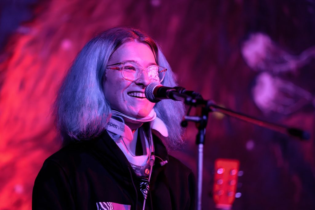 persoon met nekbrace lachend achter microfoon op open podium Diversity Day