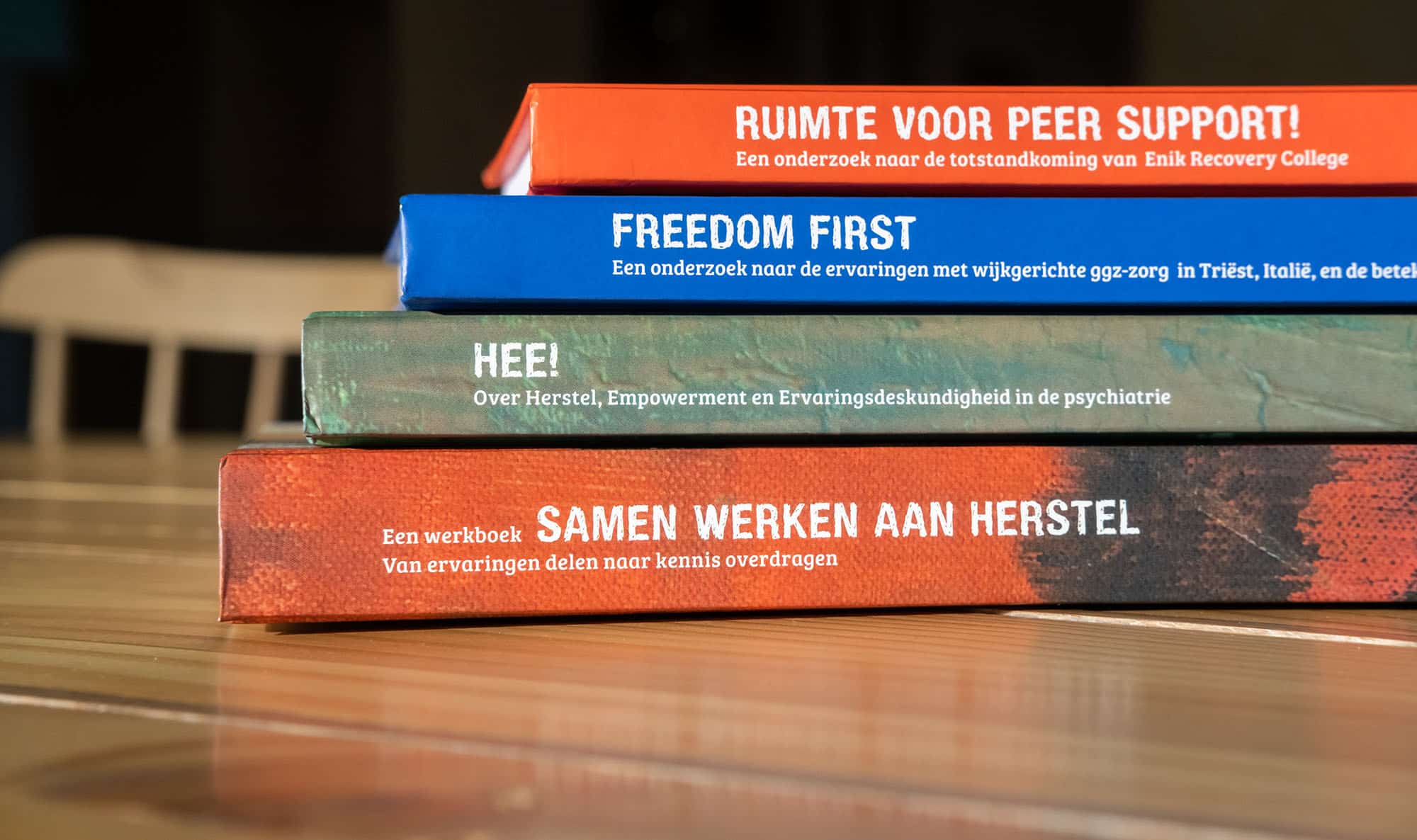 Er liggen vier boeken met de titels: Samen werken aan herstel, Hee!, Freedom first en Ruimte voor peer support.