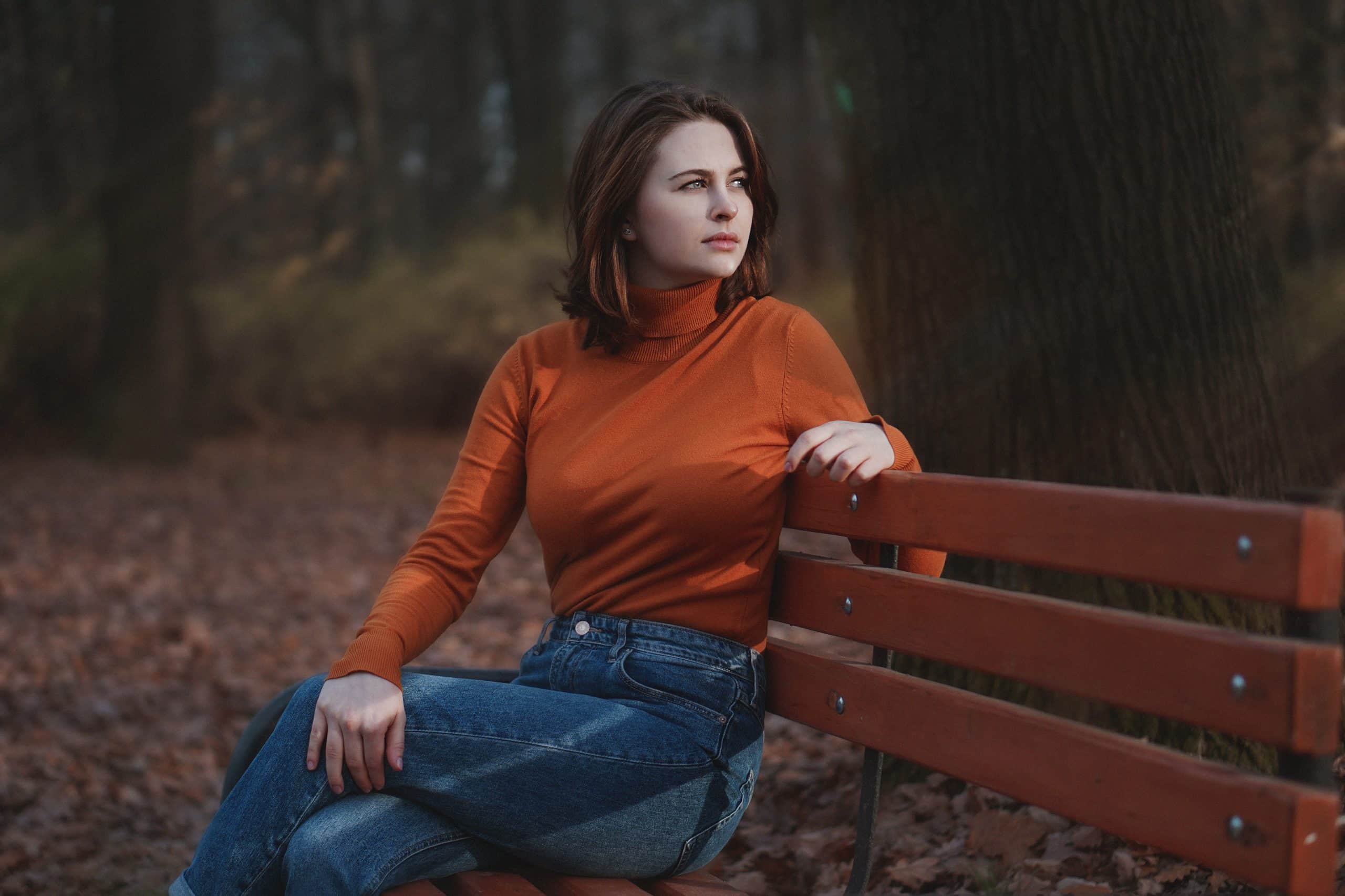Foto van vrouw op bankje in bos.
