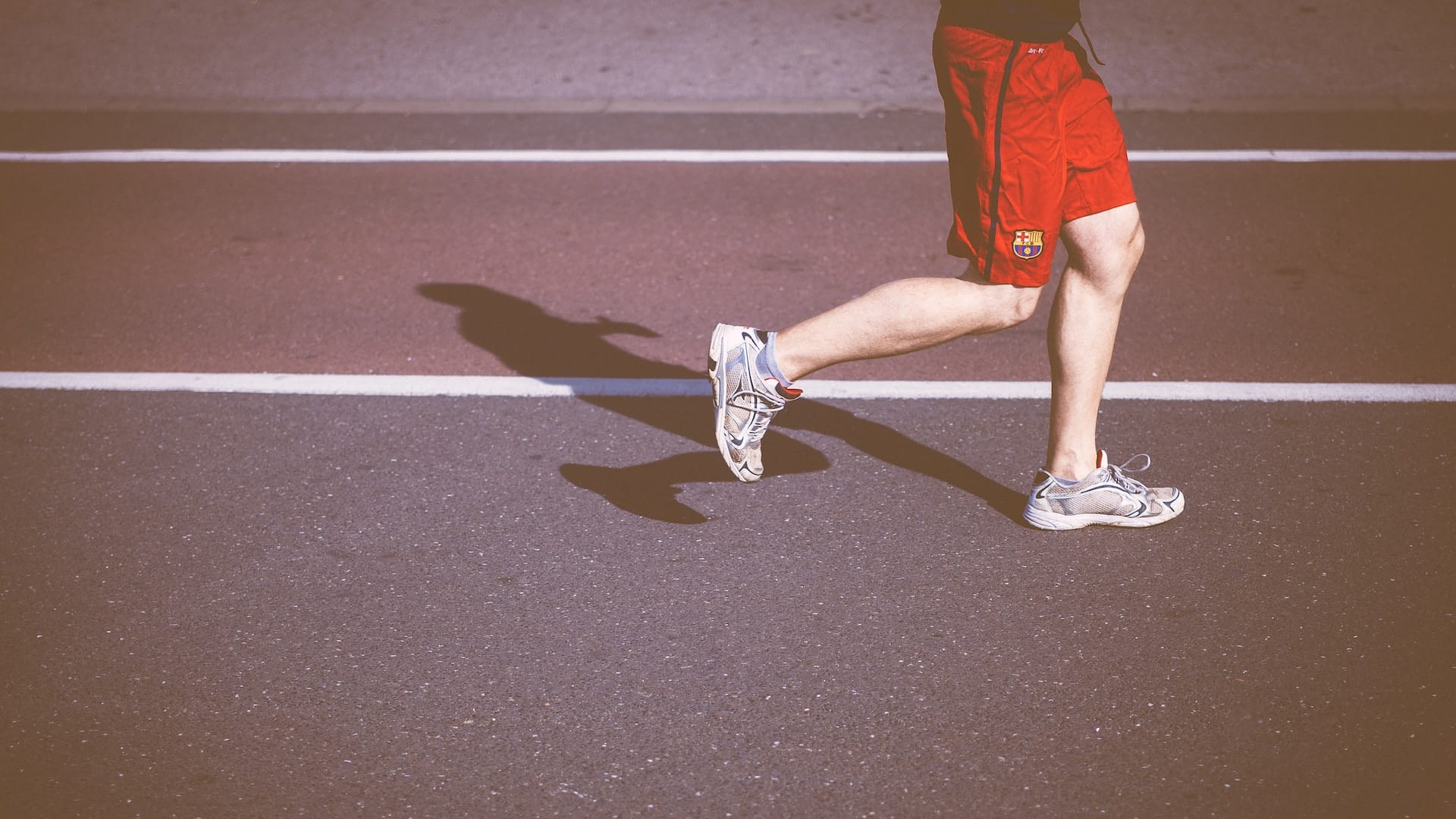 Foto van onderbenen van loper op atletiekbaan.