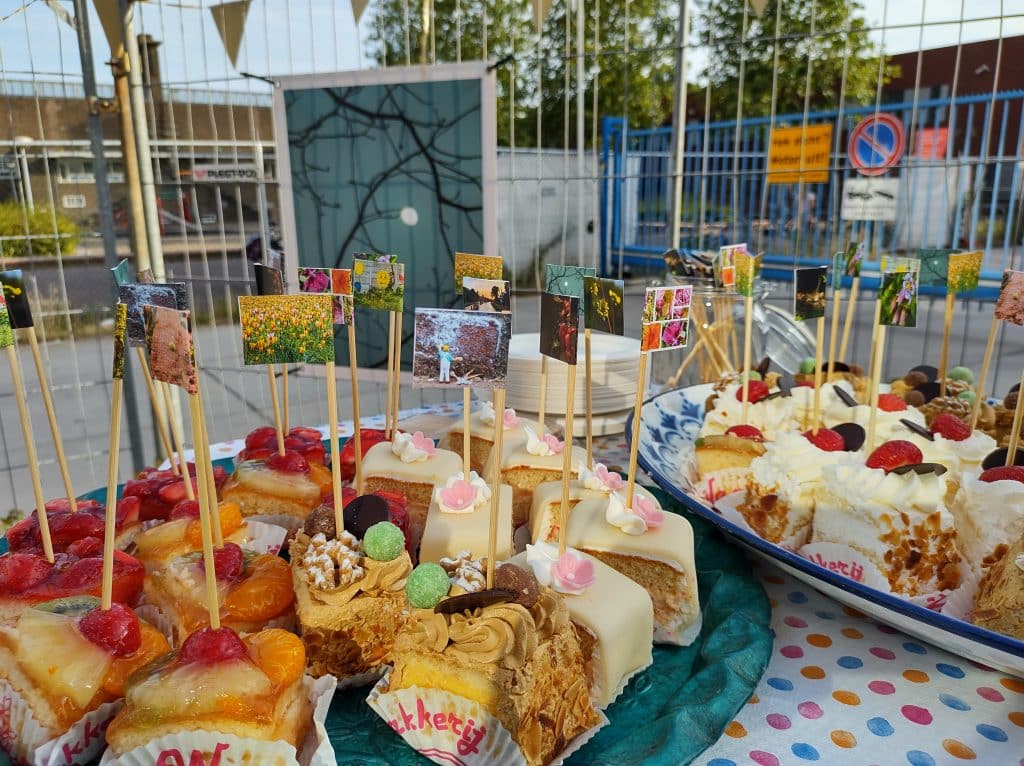 Foto van een schaal met gebakjes, erin prikkers met vlaggetjes met verschillende foto's gemaakt op de cursus.