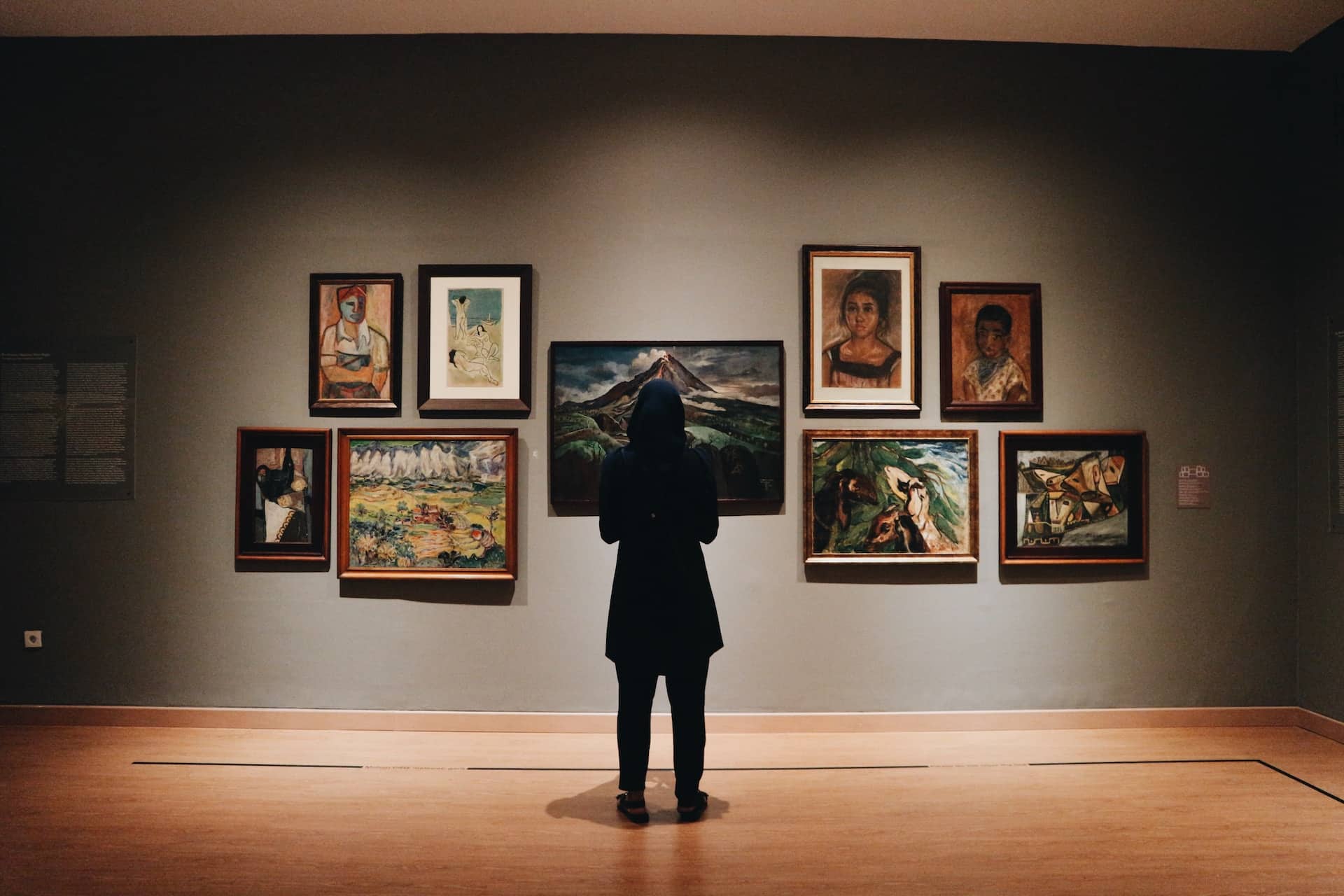 Foto van een persoon die naar schilderijen kijkt.