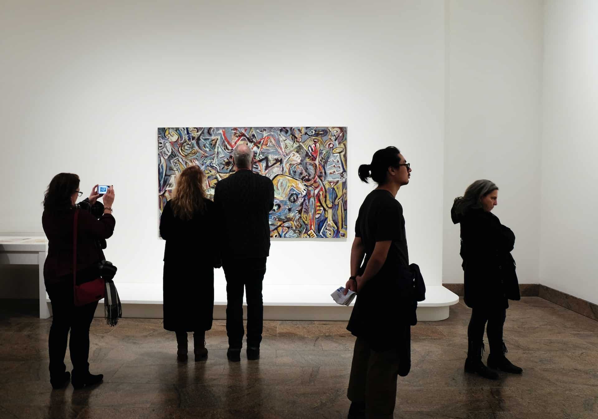 Groep mensen in het museum, met op de achtergrond een abstract schilderij.