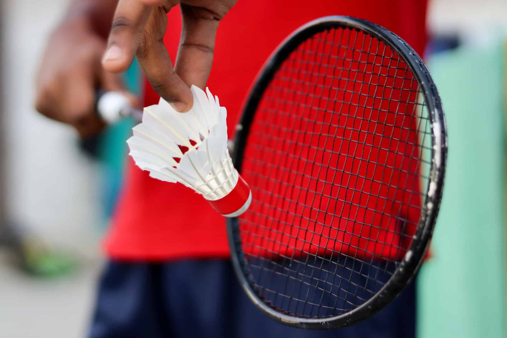 Foto van een persoon die een badminton racket en shuttle vasthoud.