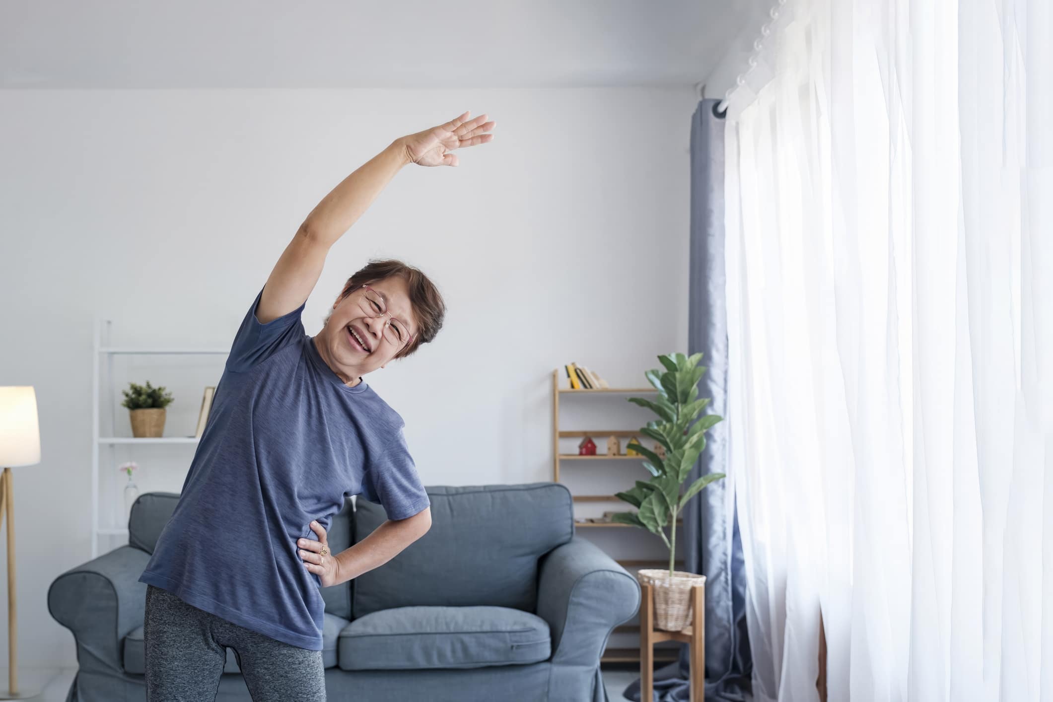 Foto van ouder persoon die in woonkamer aan het sporten is.